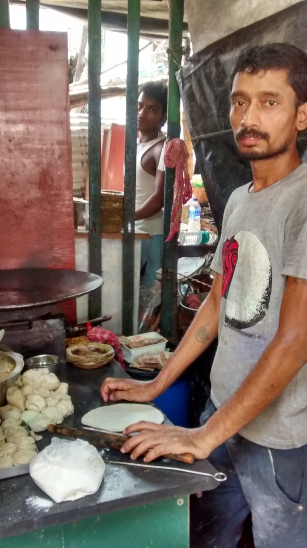 A boy rolls out dough to make a ‘kochuri’i